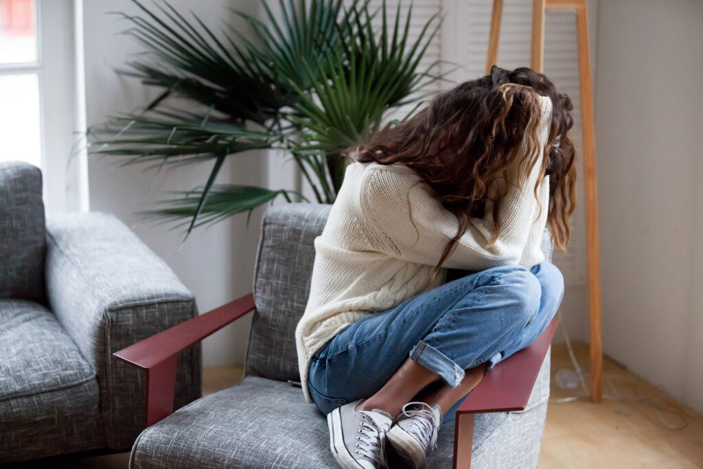 Save Download Preview Depressed sad woman holding head in hands sitting on armchair at home showing the effects of women and drugs.