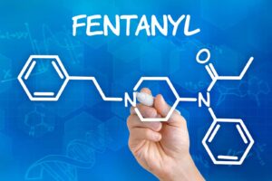 Hand with pen drawing the chemical formula of fentanyl; fentanyl analogs deaths