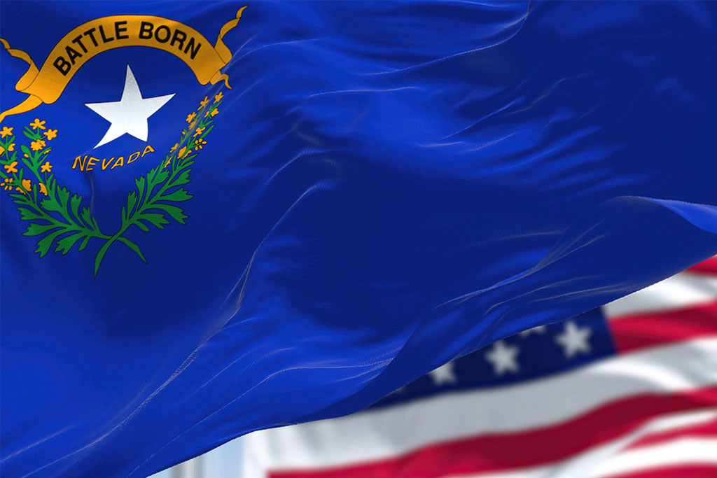 The Nevada state flag waving along with the national flag of the United States of America. In the background there is a clear sky. Nevada is a state in the Western region of the United States. Concept of Nevada Rapid Detox by Waismann Method