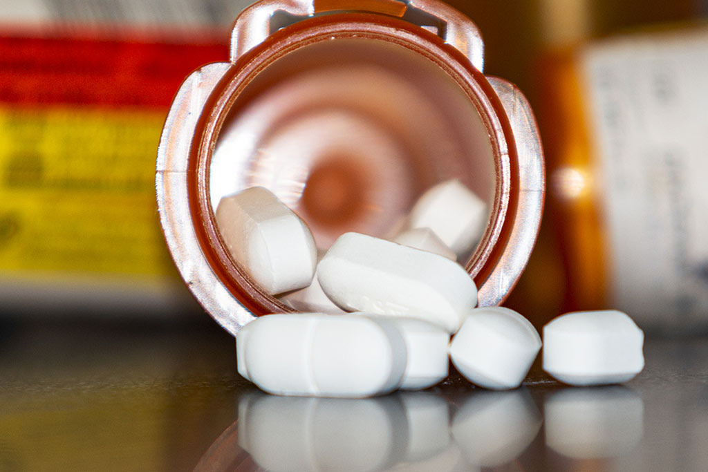 Save Download Preview Horizontal view of looking directly into an oragne pill bottle lying on a black table with white pills falling and reflecting onto a black counter. Hydrocodone warnings concepts.