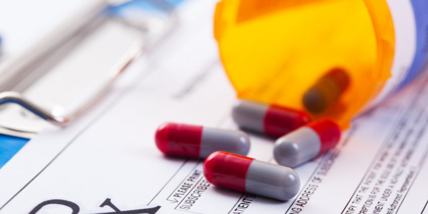 Prescription drugs spilling onto a RX prescription clipboard