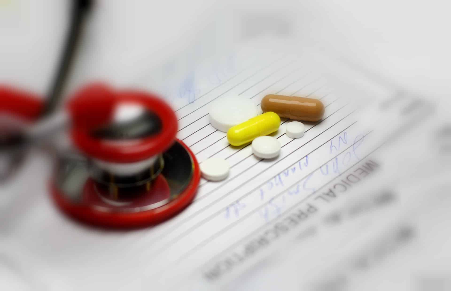Stethoscope next to pills on top of papers