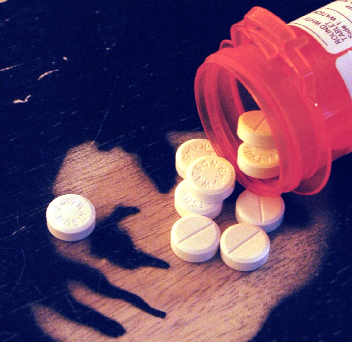 Pill bottle on a table spilled over with white pills coming out