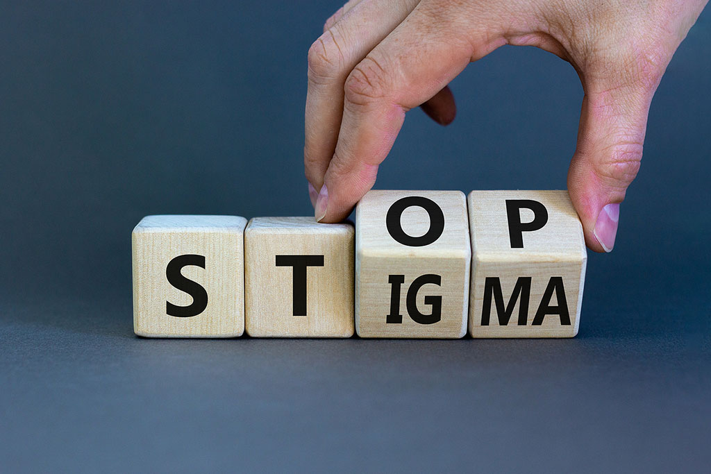 A photo of a person's hand turning cubes with words stop stigma illustrating the mythology around drug addiction and how people are treated as a result