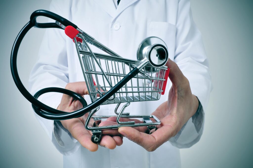 doctor holding in his hand a shopping cart with a stethoscope inside, depicting the health care industry concept