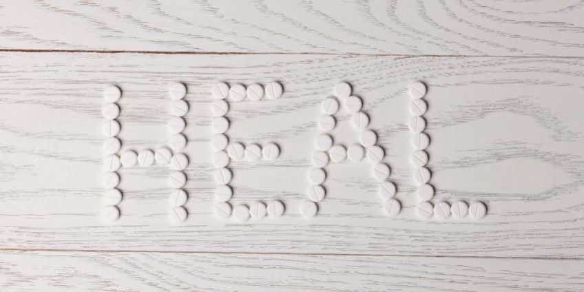 Word heal made of white pills on wooden table