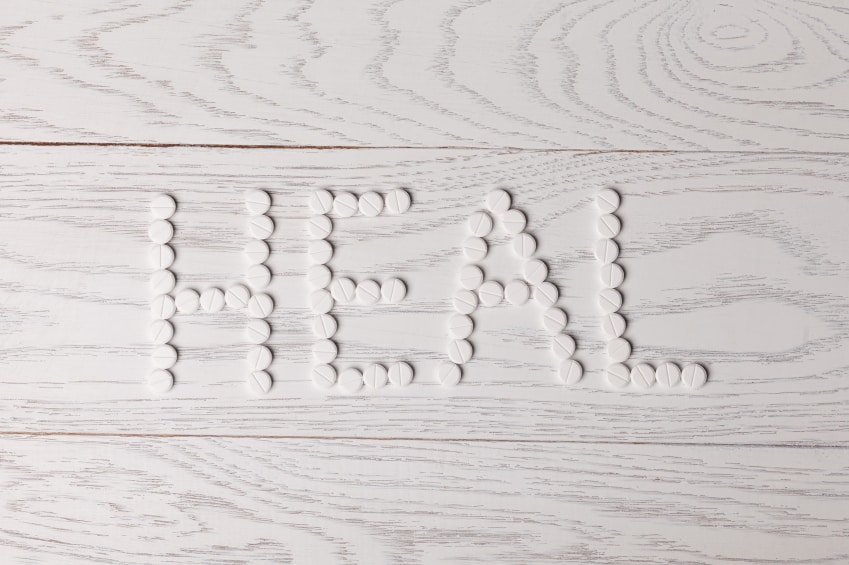 Word heal made of white pills on wooden table