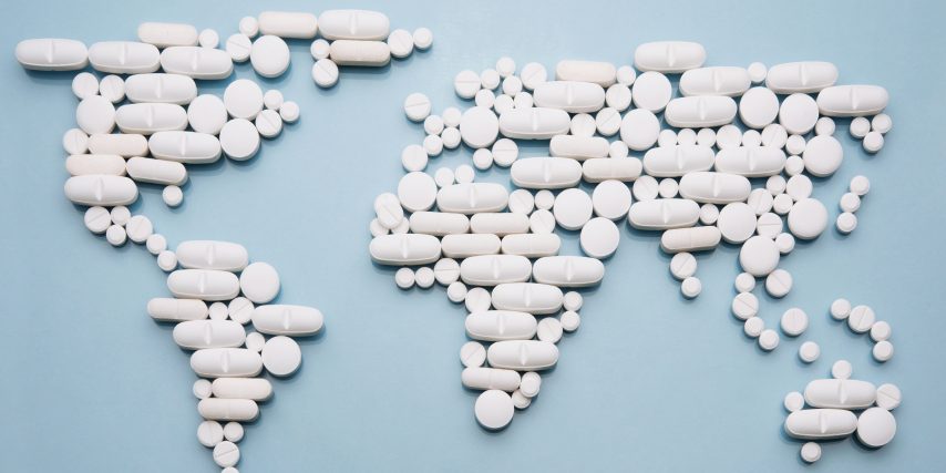 Flat map of the world made with white pills on a blue background. Illustrates the state of the acrylfentanyl public health emergency