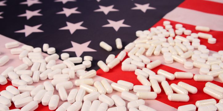 American flag with opioids white pills laid on it as part of an opioid overdose awareness campaign