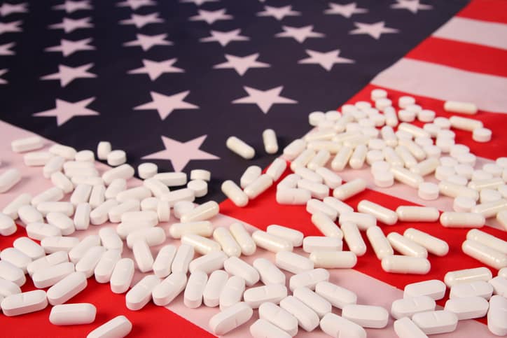 American flag with opioids white pills laid on it as part of an opioid overdose awareness campaign