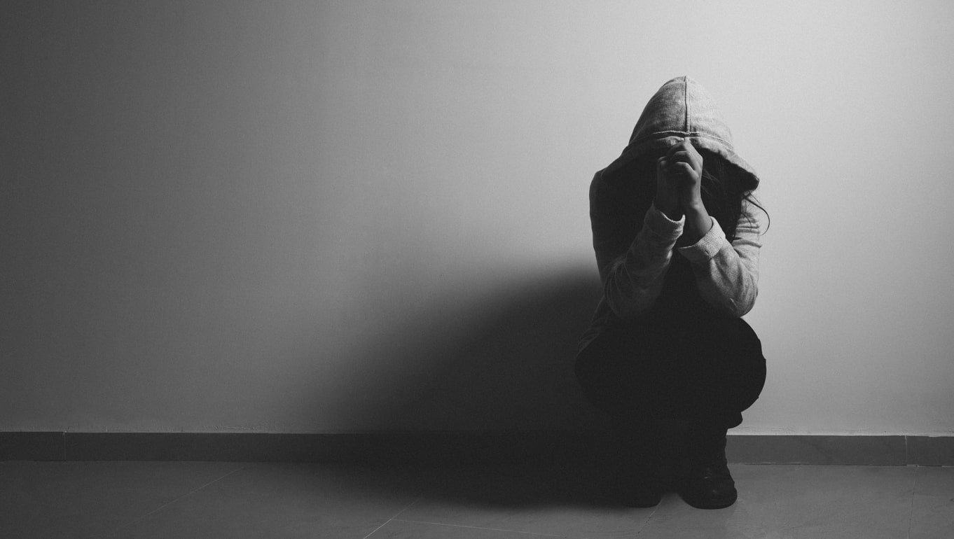 Woman crouched down looking depressed which possibly occured from being called addict