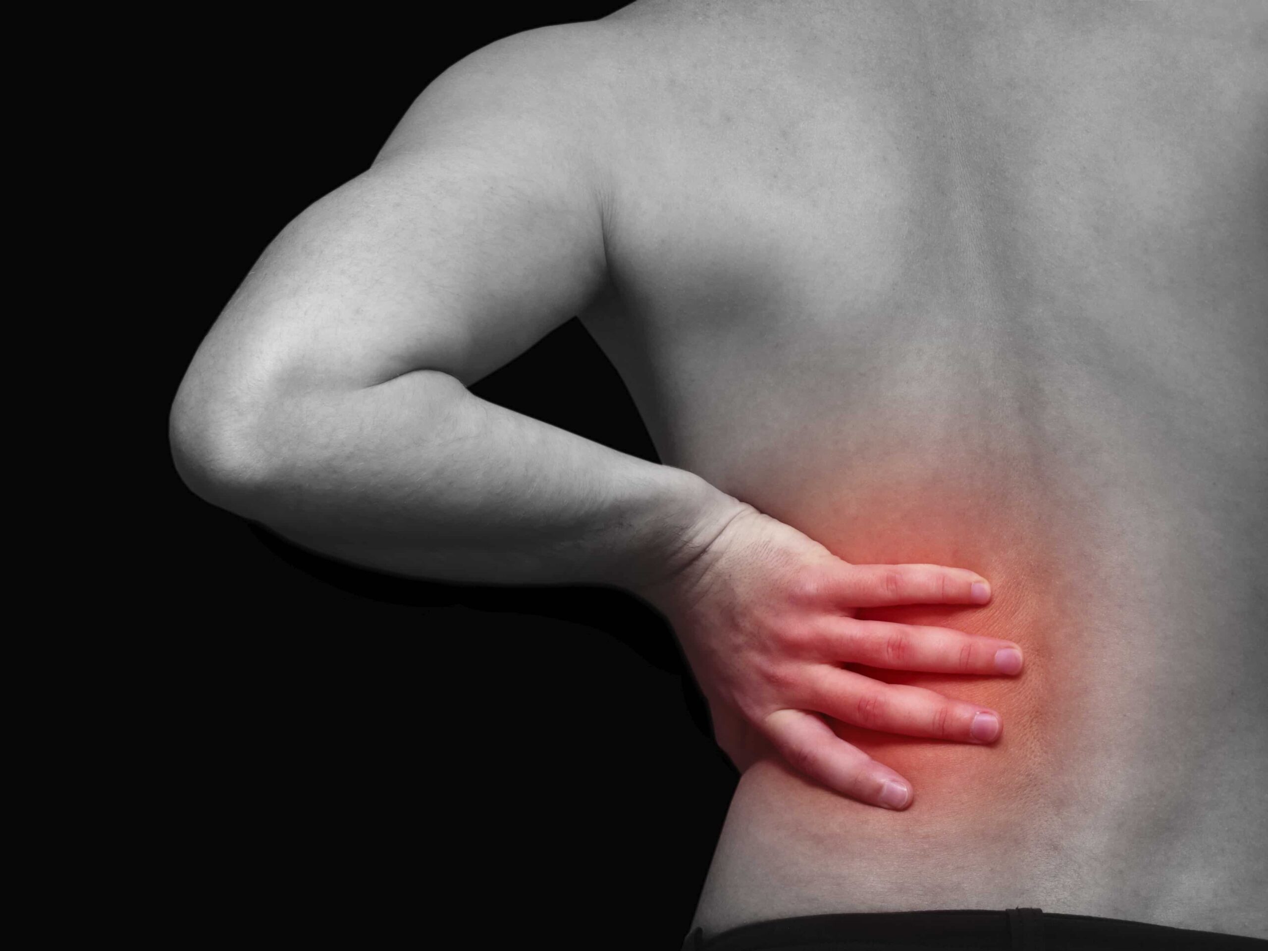 black and white image of man holding his back with red indication of pain area.