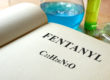 A book with fentanyl described and test tubes on a table illustrating pharmaceutical company creating fentanyl-based drugs
