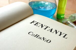 A book with fentanyl described and test tubes on a table illustrating pharmaceutical company creating fentanyl-based drugs