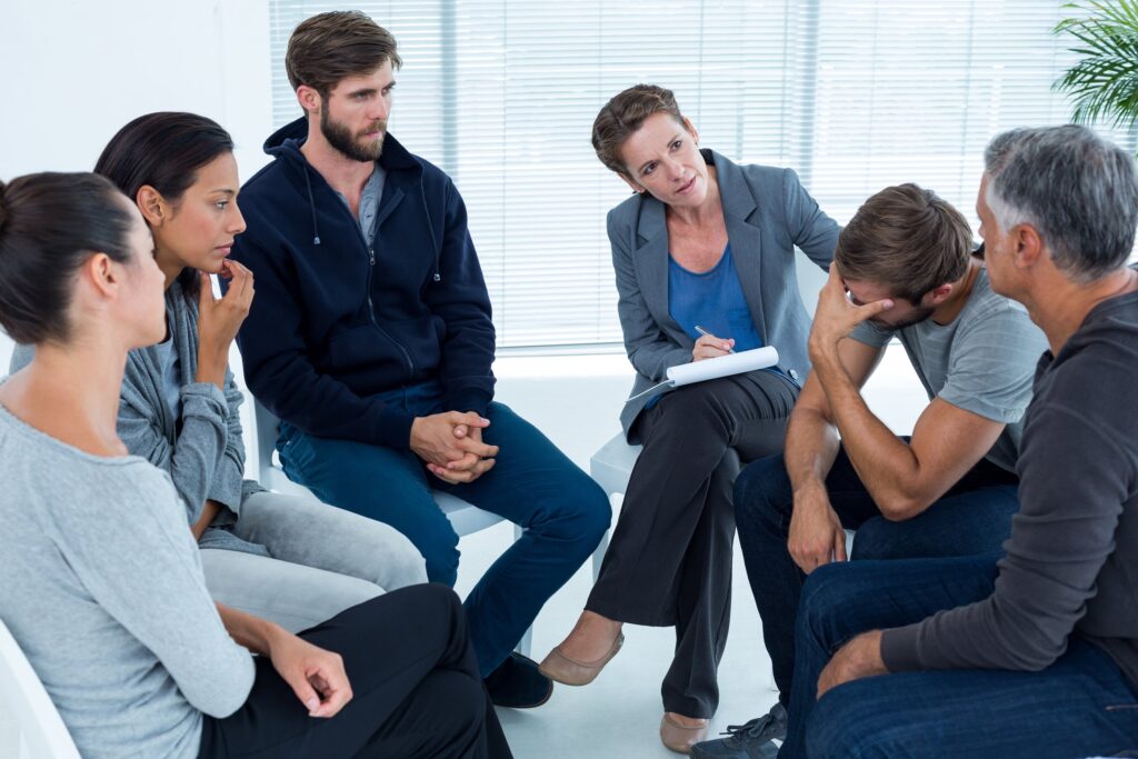 Concerned woman comforting another inopioid addiction rehab group at a therapy session