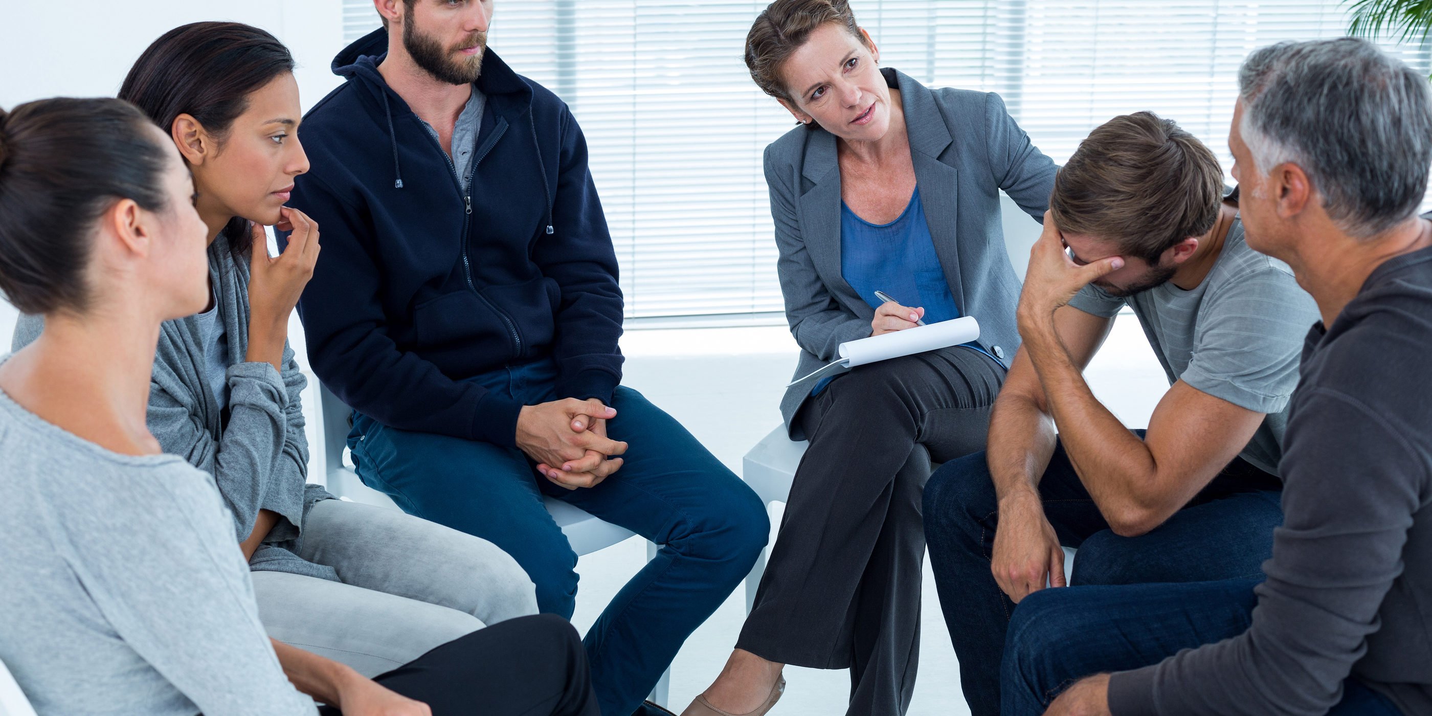 Concerned woman comforting another inopioid addiction rehab group at a therapy session