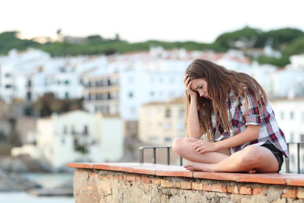 Teen sitting on ledge fighting opioid addiction and feel depressed and isolated