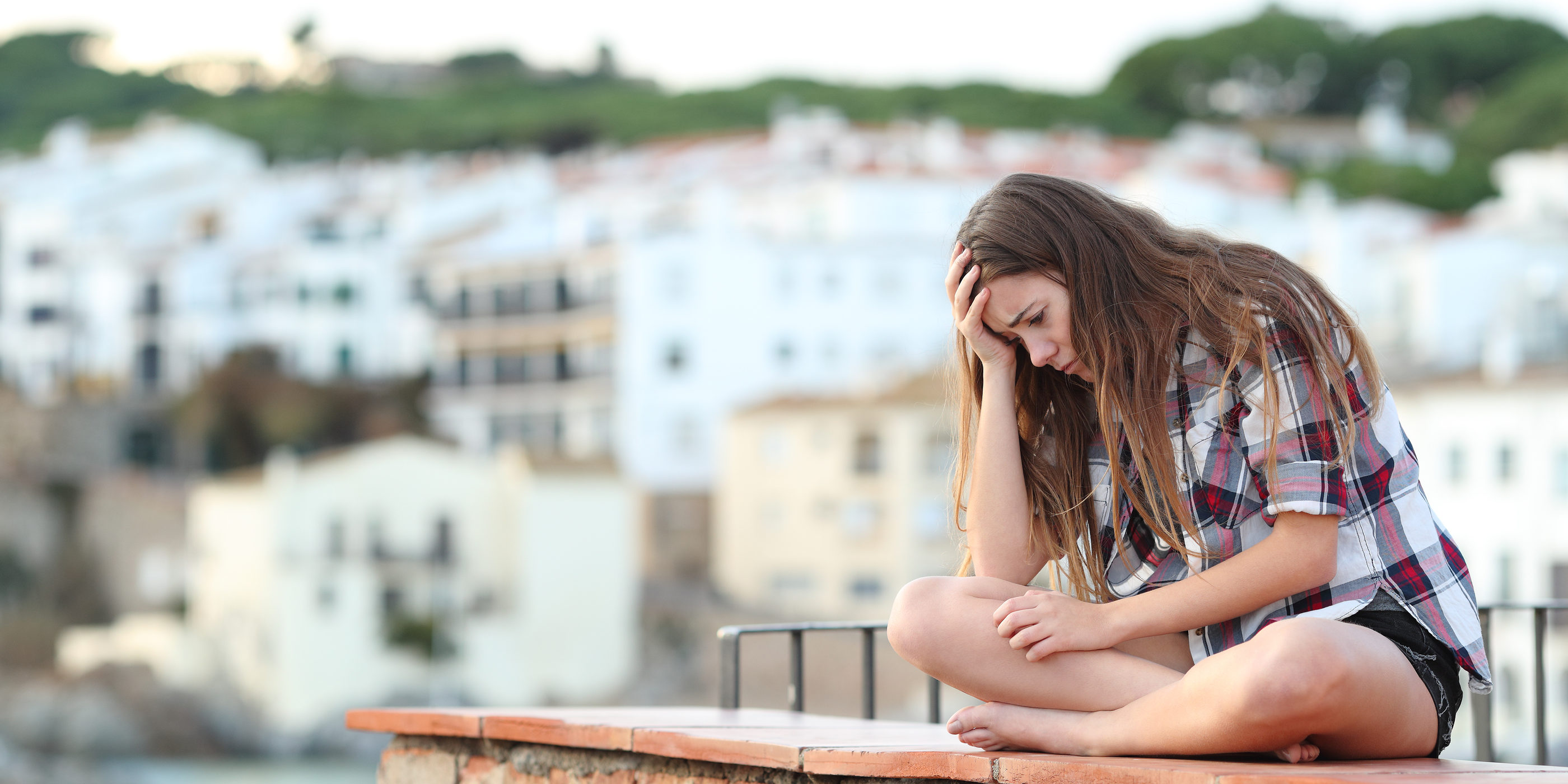 Teen sitting on ledge fighting opioid addiction and feel depressed and isolated
