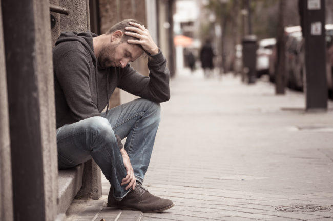 depressed man struggling with opioid dependence sitting on sidewalk