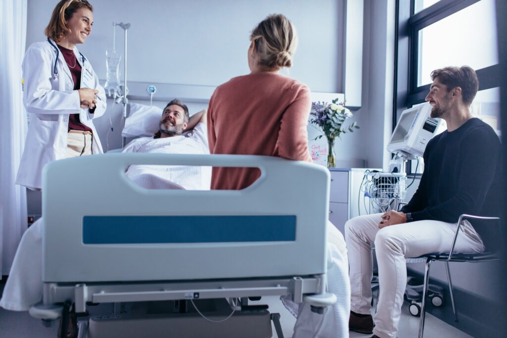 man in hospital bed surrounded by doctor and family after successfully completing medical detox for opioids