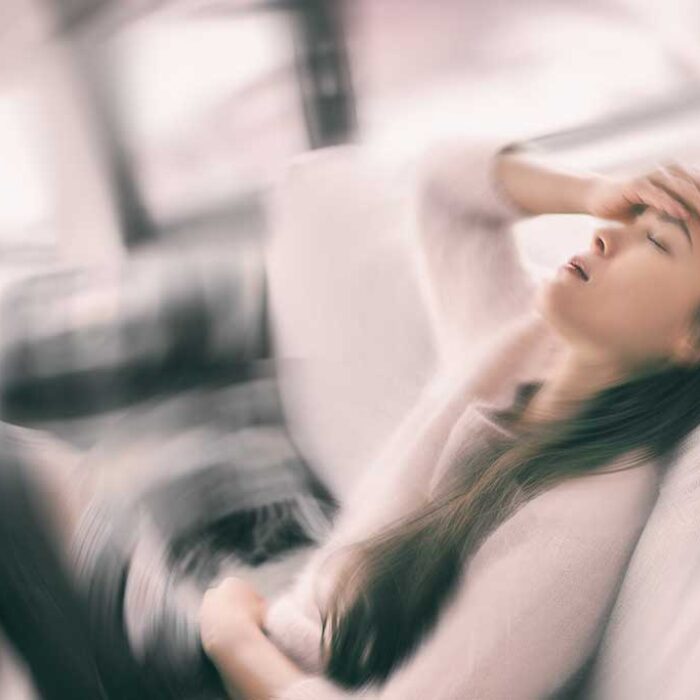 Sick woman with headache feeling faint vertigo holding head in pain with fever and migraine. Blurry motion blur background. Concept of oxycodone side effects