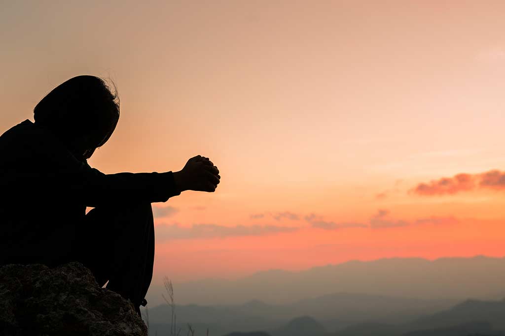 piritual prayer hands over sun shine with blurred beautiful sunset background. Woman praying to god with hopeful blessing against sunset. Concept of importance of spirituality in addiction recovery