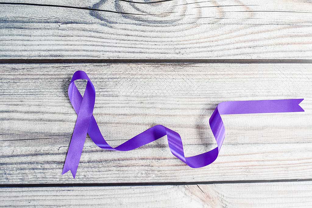 Concept of opioid overdose increase: photo of a purple ribbon on a wooden table for International Overdose Awareness Day