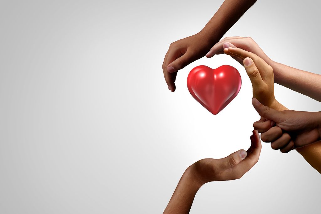 Photo of hands in a shape of a human head with a rubber heart inside it representing concept of recognizing individual mental health in substance use treatment