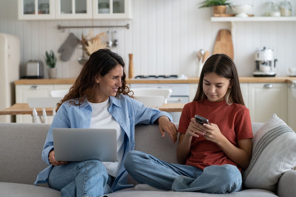 Photo of a young smiling mother talking to teen daughter child about online safety; concept of drugs parents must watch for.